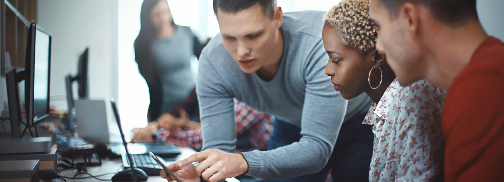 Closeup side view of group of mid 20's mobile application developers testing the code and fixing the issues 