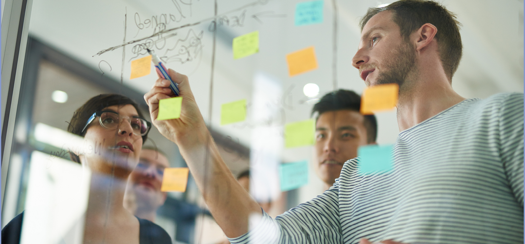 Cropped shot of coworkers using sticky notes on a glass wall during a meeting